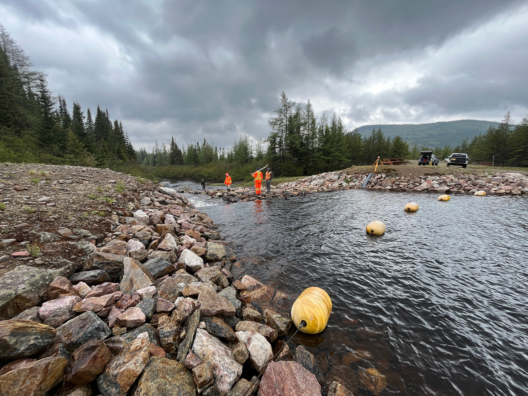 Travailleurs près d'une rivière, nuages.