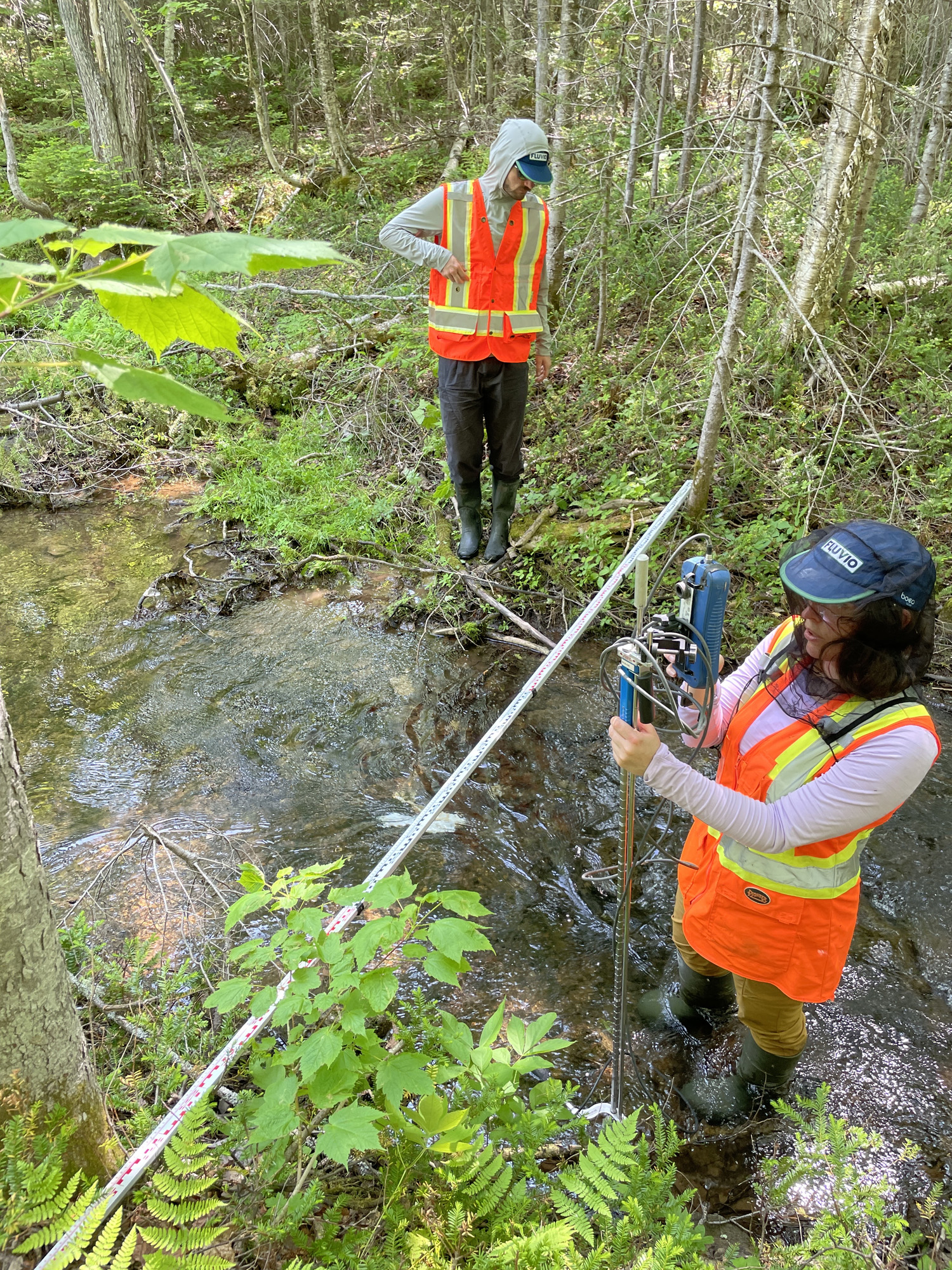 Deux personnes mesurant un ruisseau.