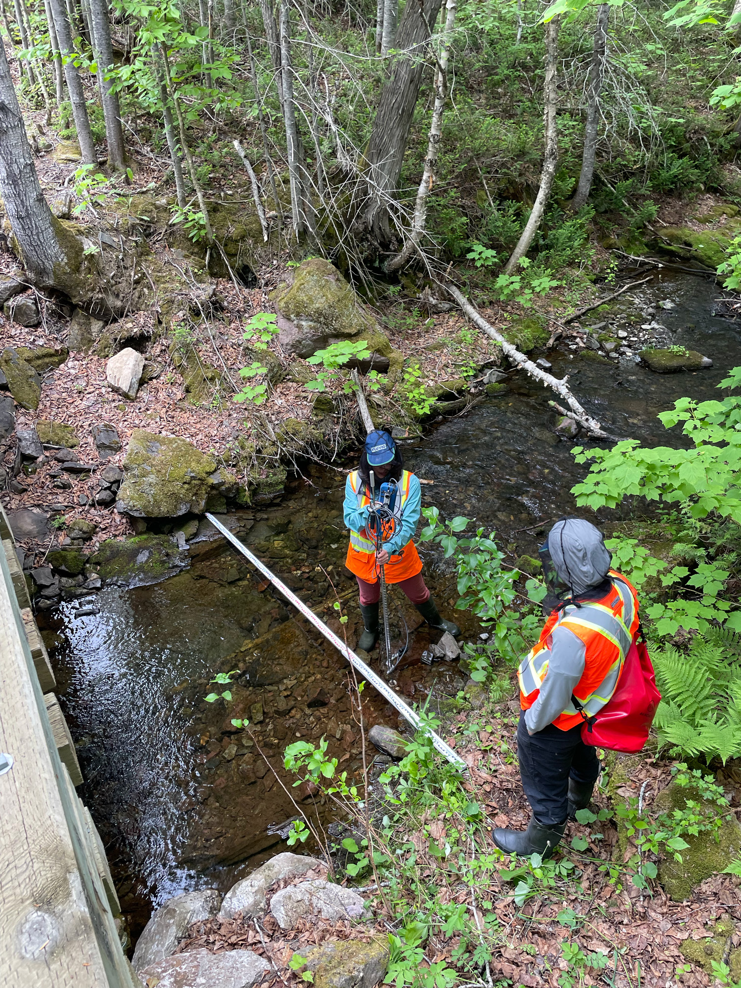 Deux personnes mesurant un ruisseau