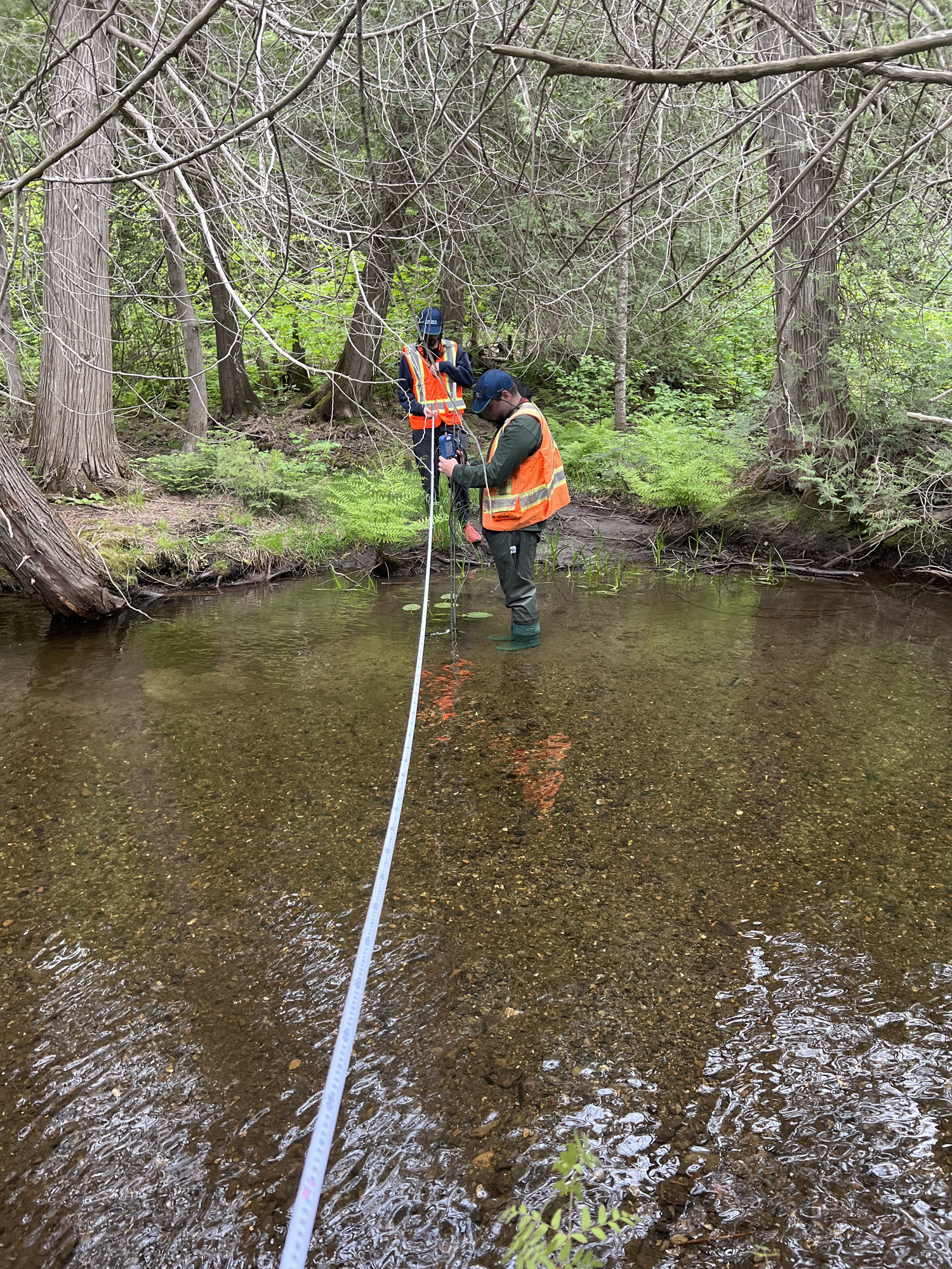 Deux personnes mesurent un cours d'eau.