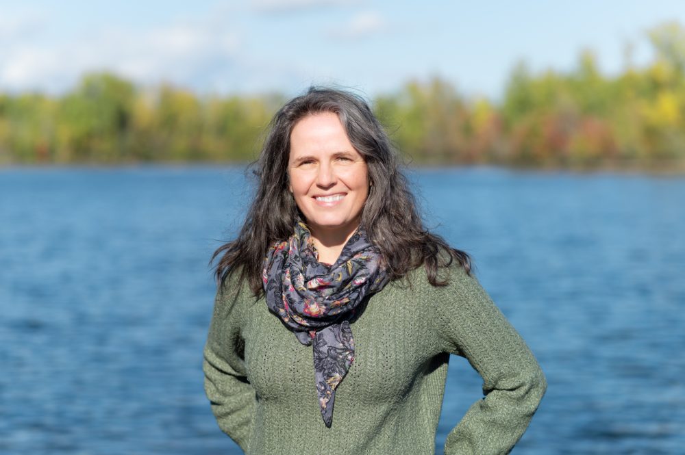 Femme souriante près d'un lac.